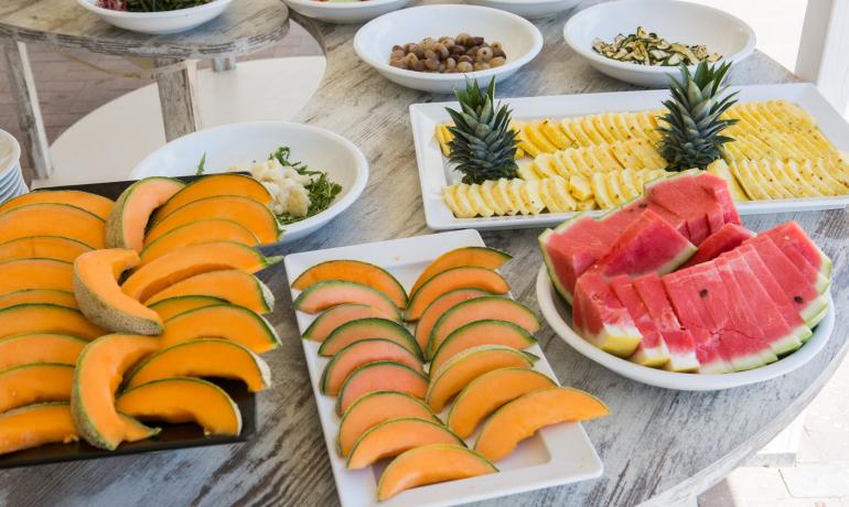 Un buffet con frutta fresca: melone, anguria, ananas e altre verdure.