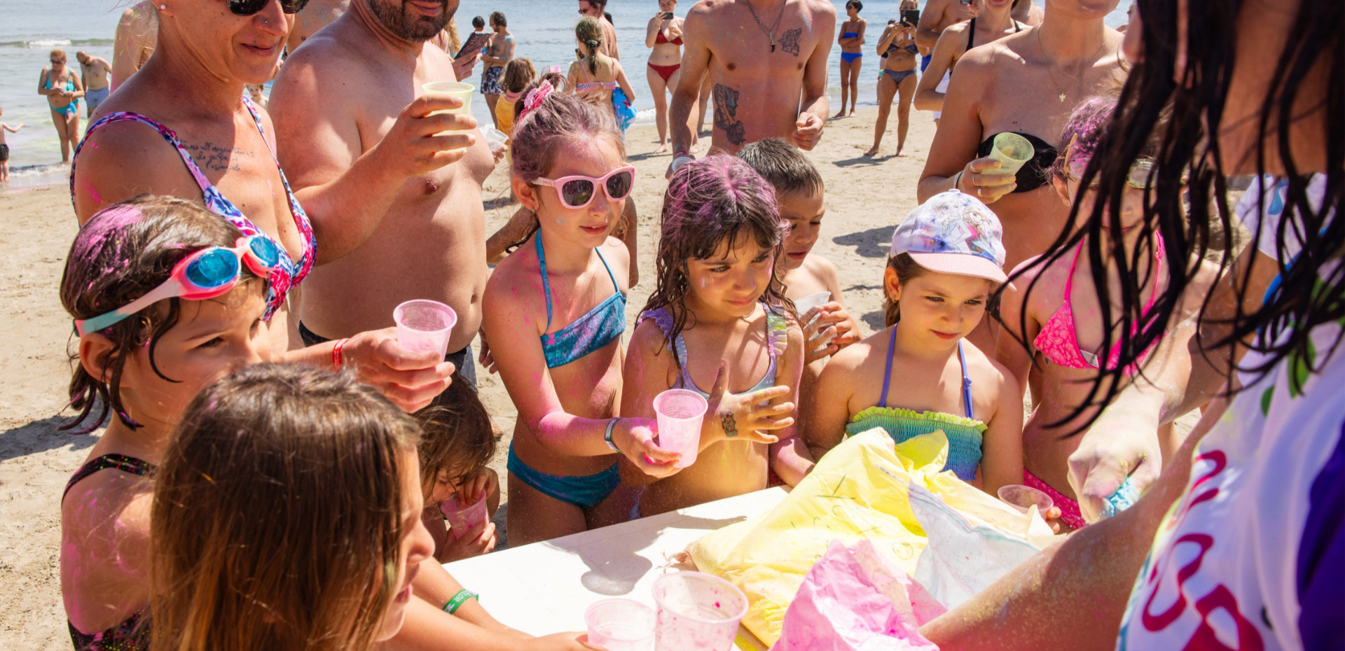 Happy families play on the beach, splashing vibrant colors under the sun.