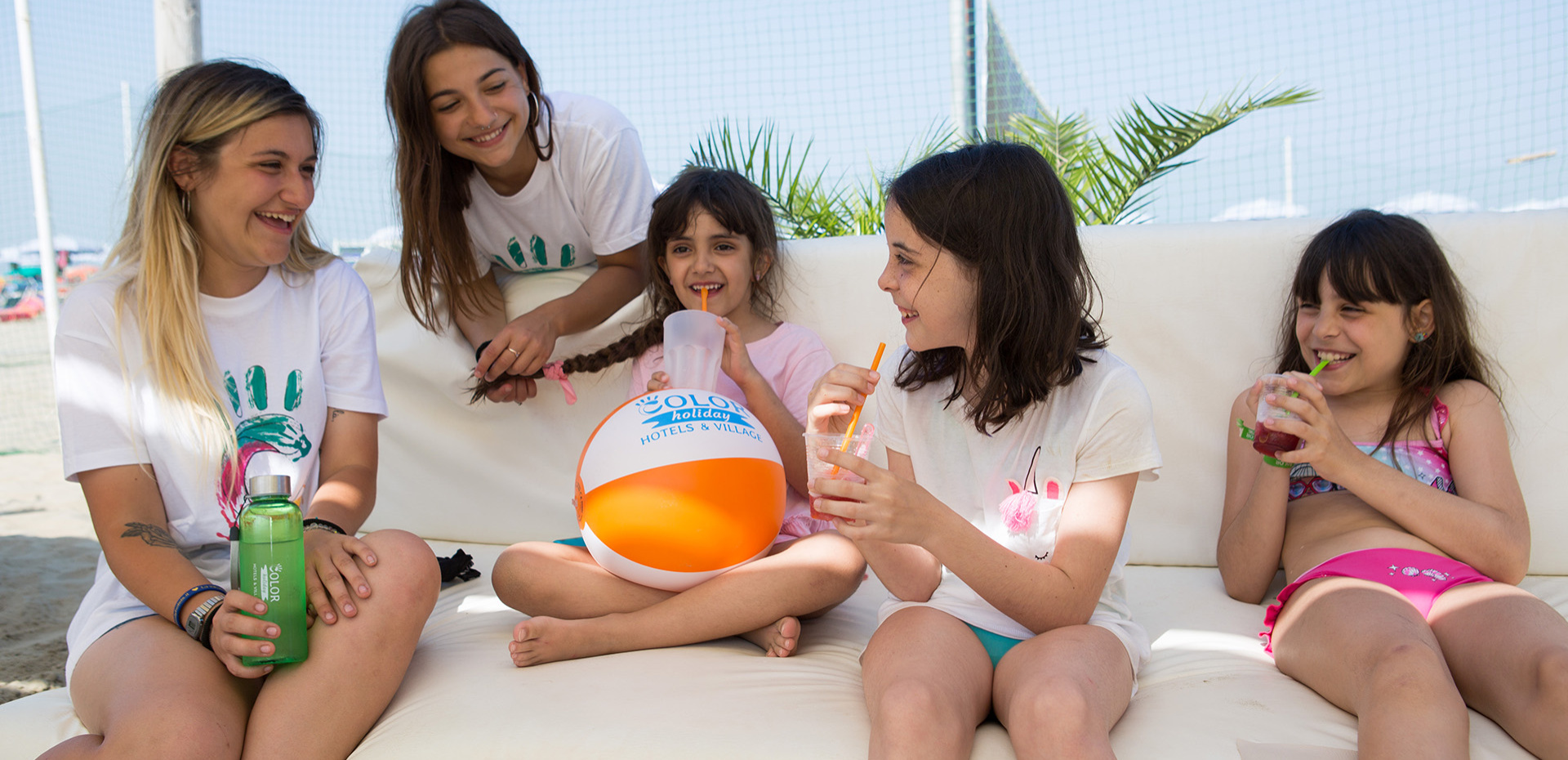 Famiglia in camera d'albergo, bambini giocano sui letti con peluche colorati.